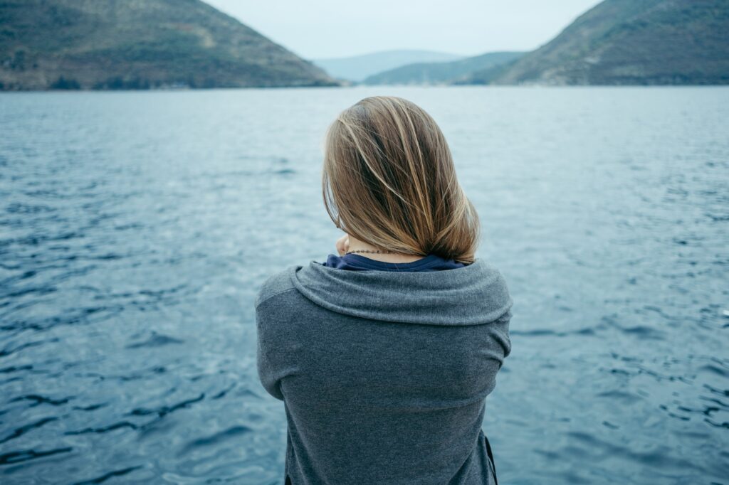 Back view of woman thinking alone and watching the sea