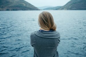 Back view of woman thinking alone and watching the sea