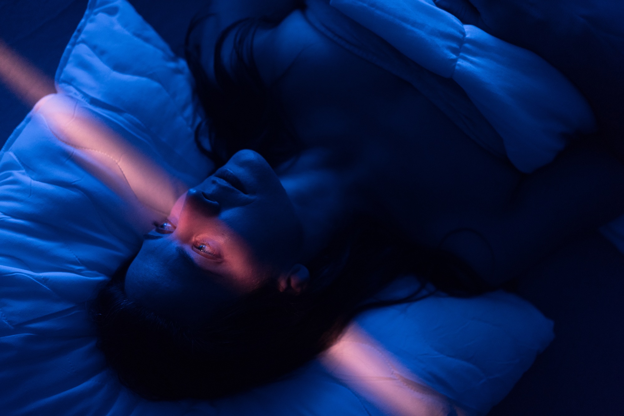 Close-up of lonely woman suffering from insomnia and depression, lying sleepless in bed at night
